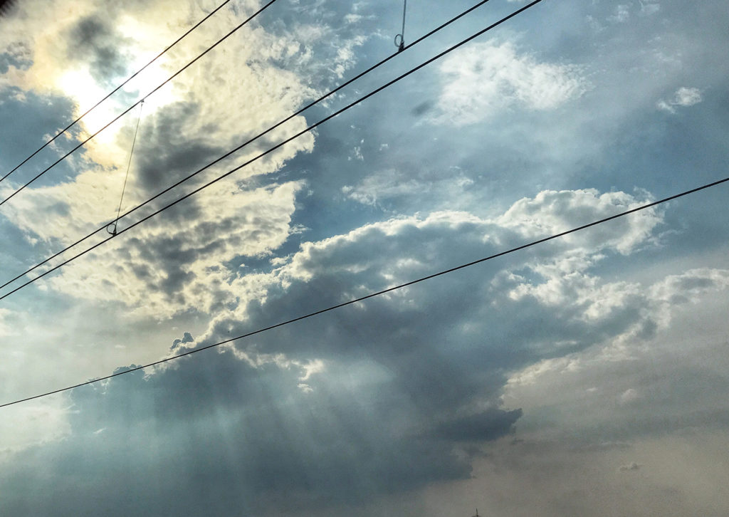 Elektrische Oberleitung einer Bahnstrecke vor bewölktem Himmel