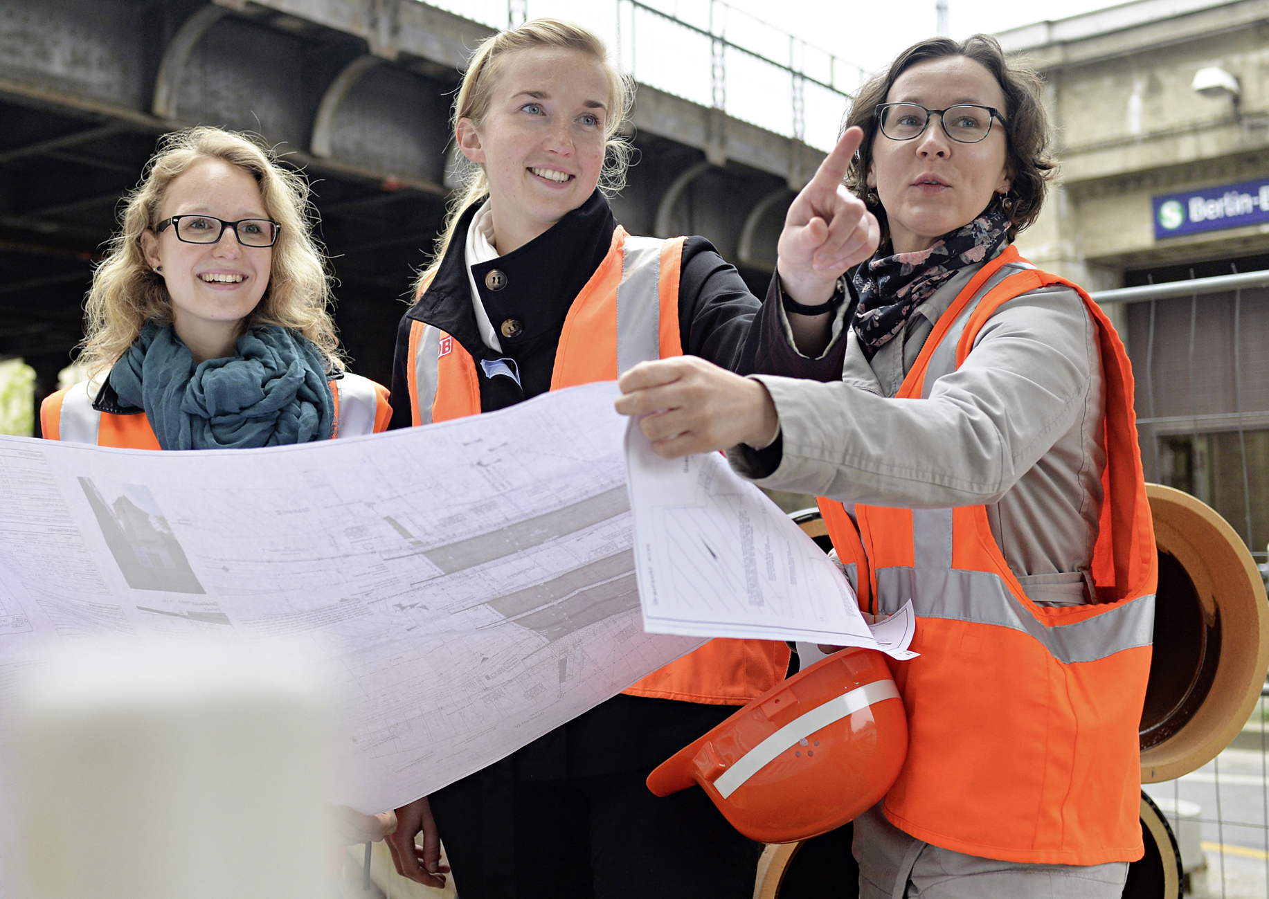 Weibliche Bahningenieure mit technischen Unterlagen an einem Bahnhof